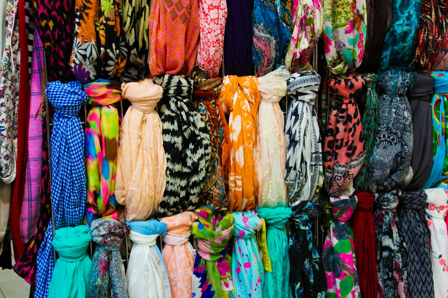 Colorful scarves hanging vertically on metal rods in a shop.