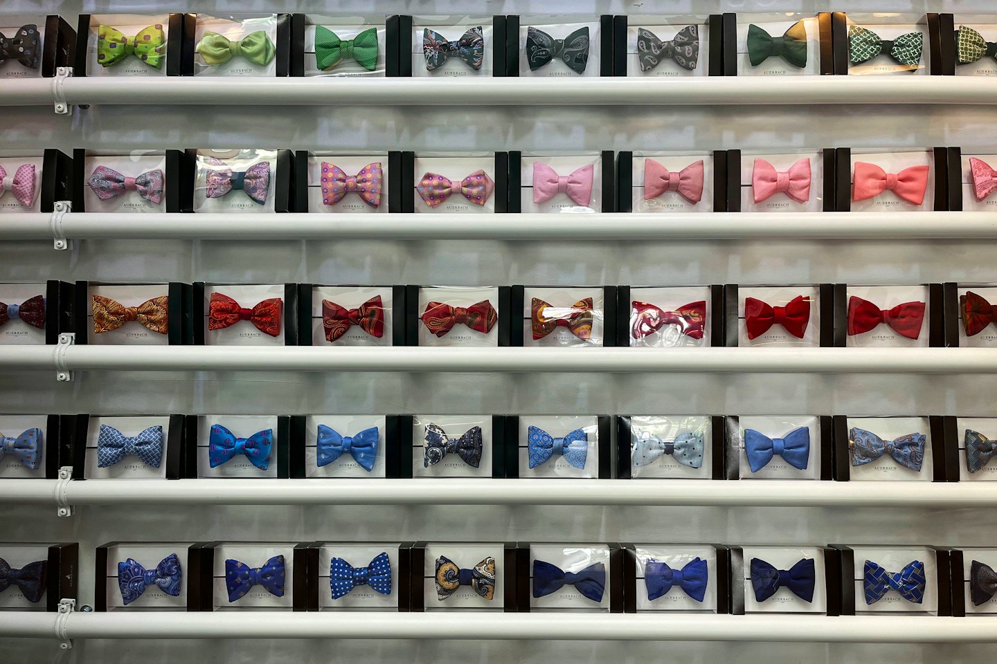 Neatly boxed bow ties in various colors displayed on store shelves.