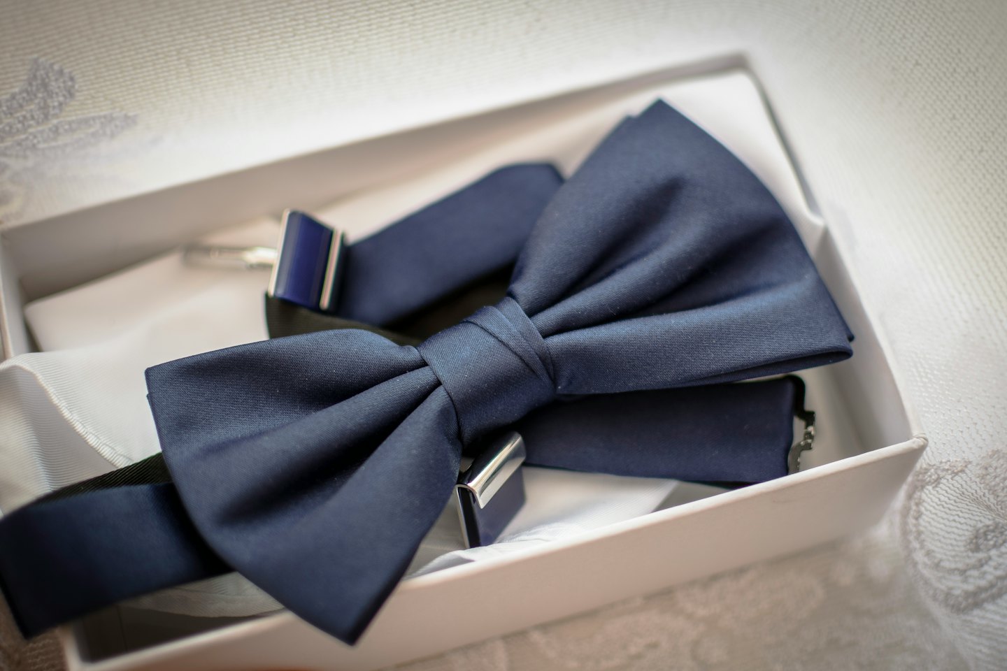 Blue satin bow tie and white pocket square in gift box.
